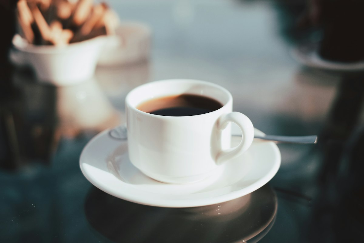 A white cup of black coffee on a saucer